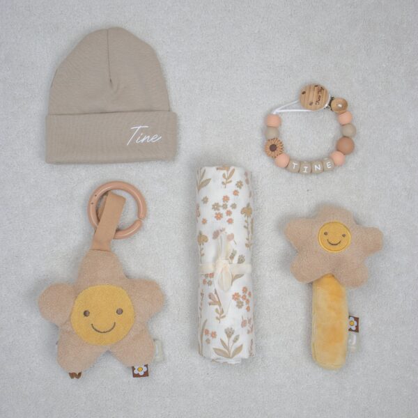 Cadeaupakket met daarin muts met naam, rammelaar, hydrofiele doek, speenkoord met naam, wagenhanger bloemen thema